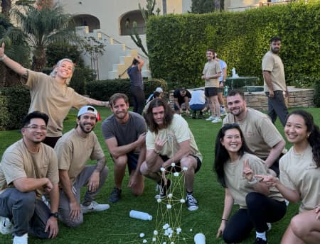 Hex team members playing a tower-building challenge on a lawn during a company offsite